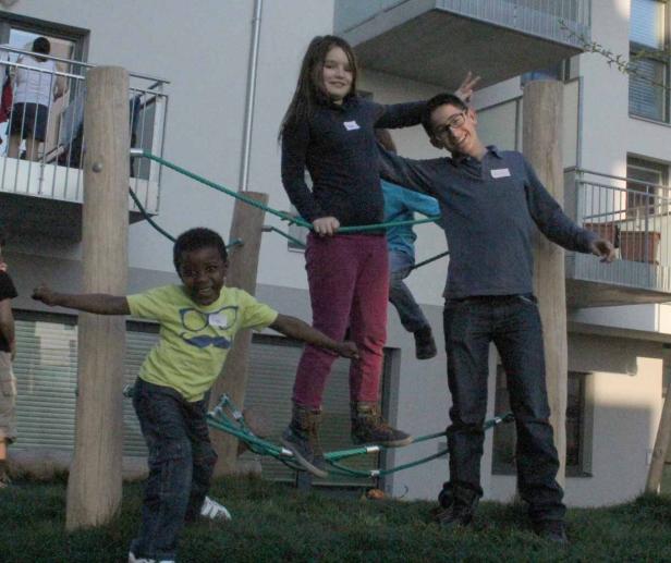 Drei Kinder spielen auf einem Klettergerüst im Freien.