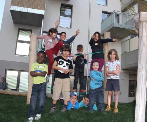 Eine Gruppe von Kindern posiert auf einem Spielplatz vor einem modernen Gebäude.