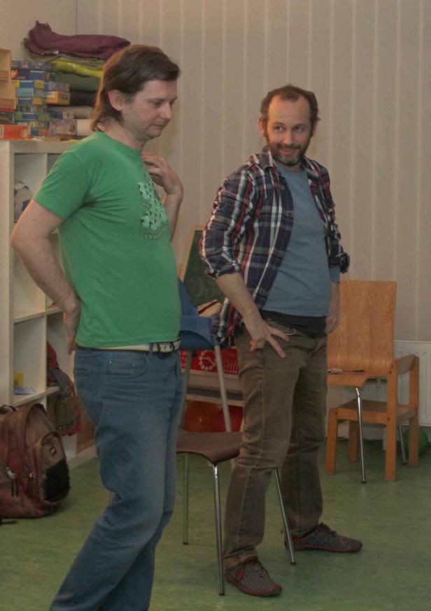 Zwei Männer stehen in einem Raum und unterhalten sich.