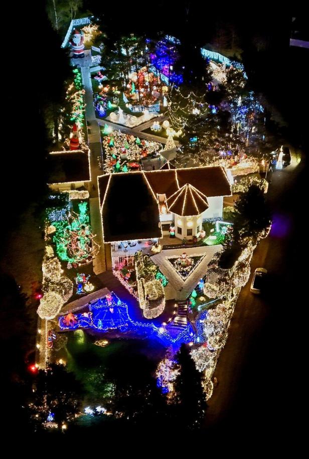 Ein Haus und Garten sind üppig mit bunten Weihnachtslichtern, Figuren und Dekorationen geschmückt.