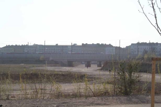 Ein Zug fährt über eine Brücke in einer städtischen Umgebung.