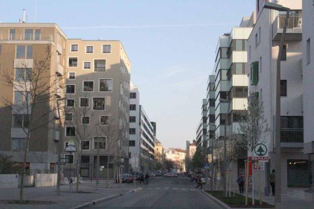 Eine Straße in Wien mit modernen Wohngebäuden und einem SPAR-Markt.