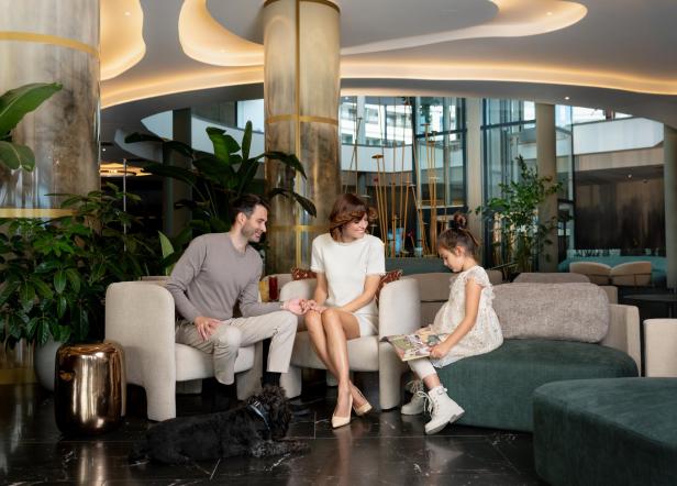 Ein Mann und eine Frau sitzen mit ihrer Tochter in einem Hotel in der Lobby. 