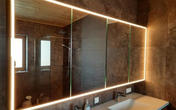 Badezimmer mit einem Spiegel und Beleuchtung über dem Waschbecken.