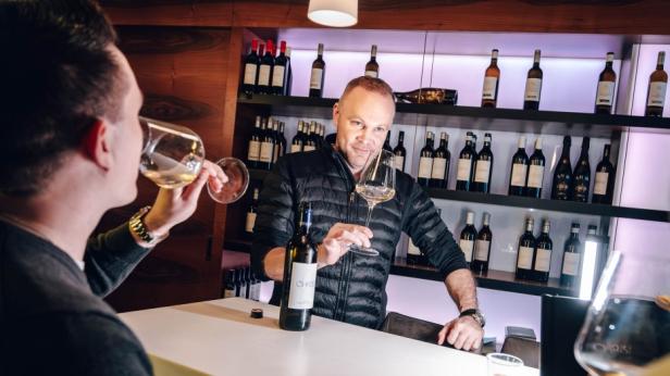 Ein Mann schenkt Wein in ein Glas ein.