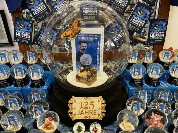 Mehrere Schneekugeln mit Wiener Motiven und ein Schild mit der Aufschrift „125 Jahre“ sind dekorativ arrangiert.