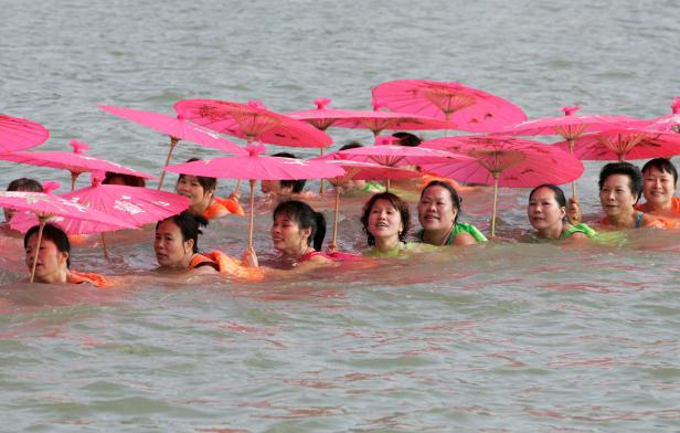 Winter swimmers hold umbrellas whilst swimming in Yong River in Nanning