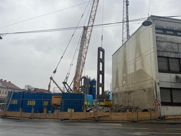 Blaue Porr-Baucontainer, dahinter sind Kräne zu sehen. 