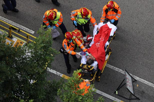 An injured resident is carried into an ambulance after a major fire engulfed bamboo scaffolding across multiple blocks at Wang Fuk Court housing estate, killing at least 44 people and leaving almost 300 missing missing, in Tai Po, Hong Kong