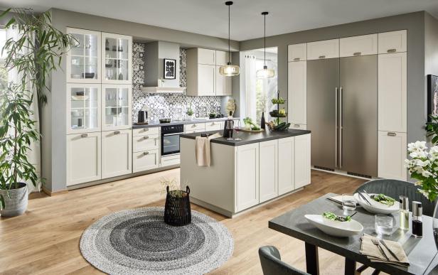 Moderne, helle Küche mit Kücheninsel, großen Einbauschränken, Esstisch und viel Tageslicht, dekoriert mit Pflanzen und Geschirr.