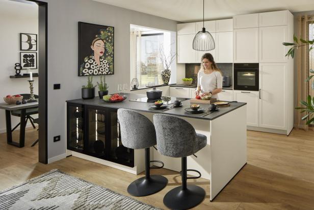 Eine Frau schneidet Gemüse in einer modernen, hellen Küche mit Kochinsel und stilvoller Einrichtung.