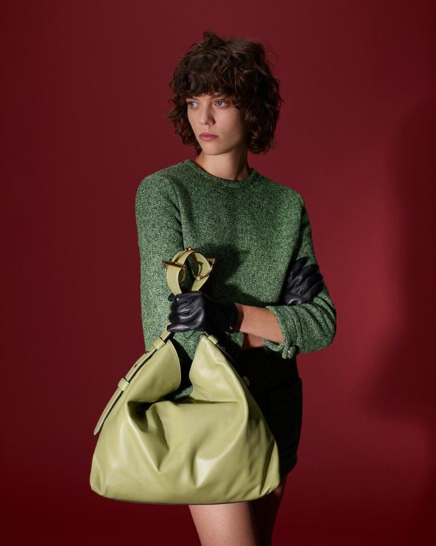 Eine Frau mit grünem Pulli und grüner Tasche