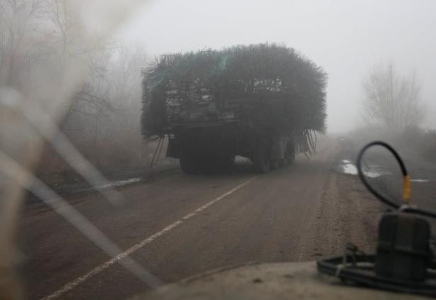 Ukrainian servicemen ride armoured personnel carrier with installed a grille as combat drones protection along a road near the front line town of Pokrovsk