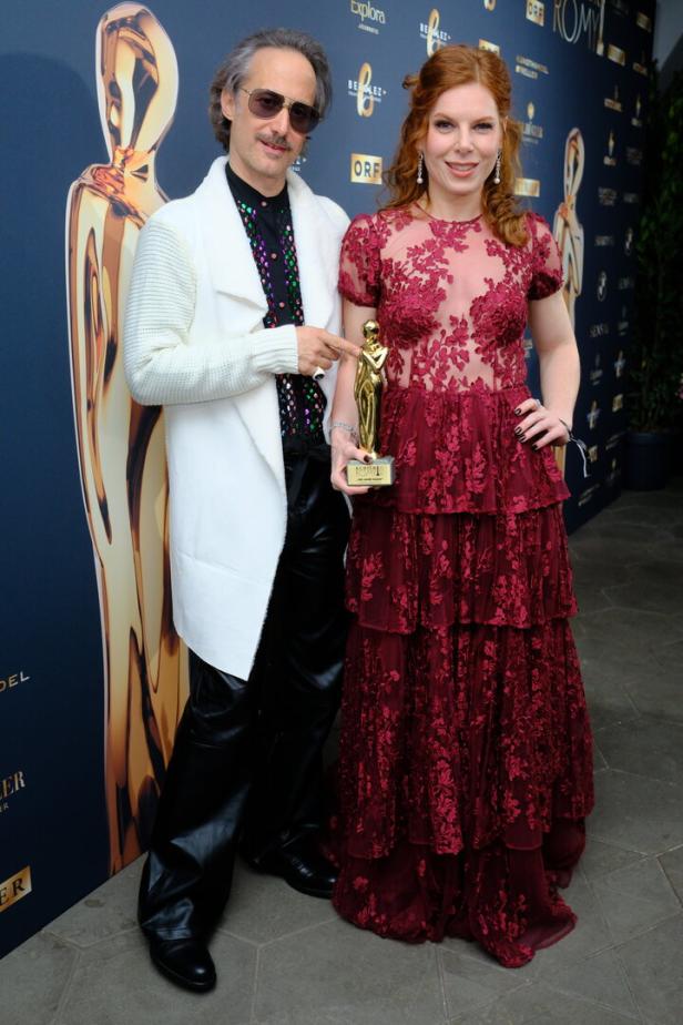 Michael Ostrowski in weiß und  Teresa Vogl im roten Kleid