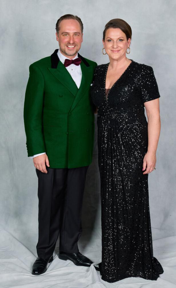 Ein Mann im grünen Anzug und seine Frau im schwarzen Kleid daneben
