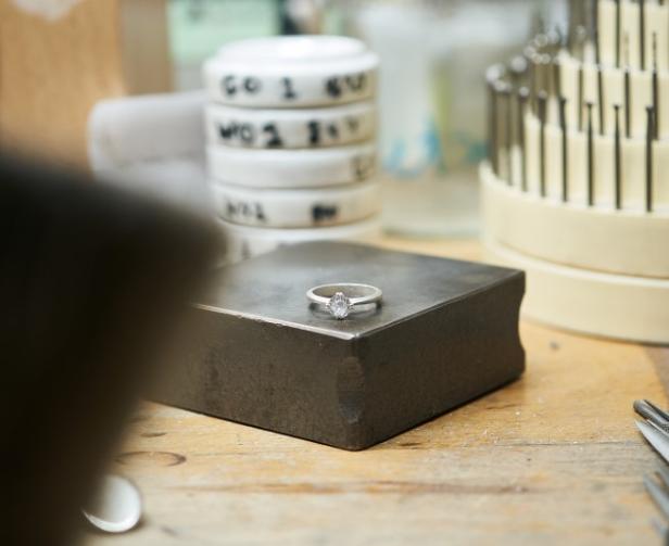 Ein silberner Ring mit einem großen Diamanten liegt auf einem Tisch.