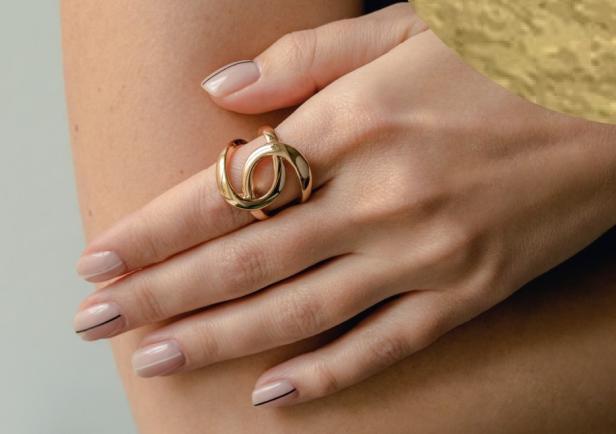 Eine Frauenhand präsentiert einen auffälligen Goldring an ihrem Zeigefinger.