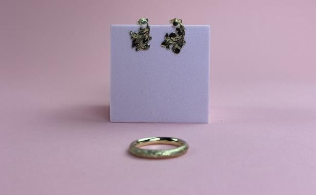 Ein goldener Ring und Ohrringe mit Steinen werden präsentiert.