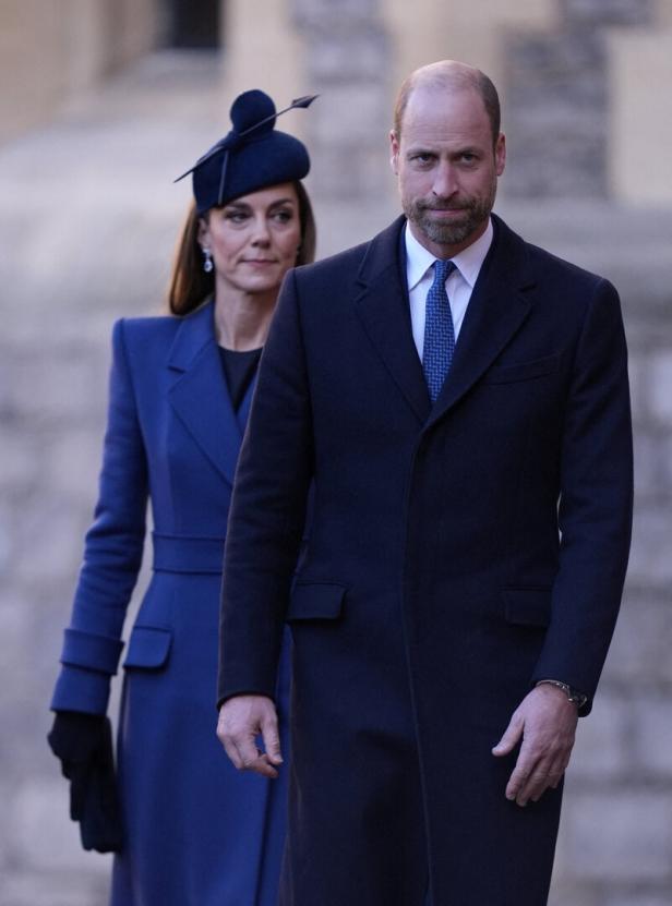 Prinz William und Prinzessin Kate in blauen Mänteln vor hellem Hintergrund.