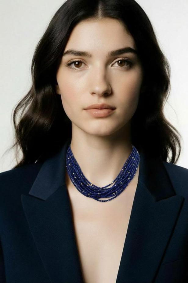 Eine brünette Frau mit einer blauen Halskette und einem blauen Blazer 