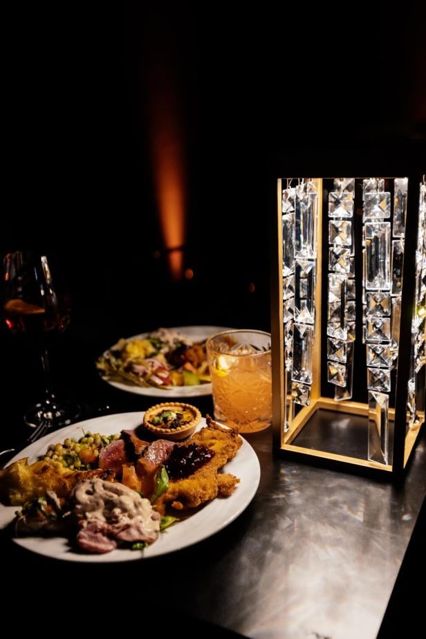 Zwei Teller mit verschiedenen Speisen, ein Getränk im Glas und eine dekorative, leuchtende Laterne auf einem Tisch.