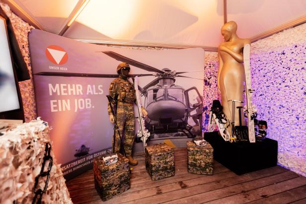 Ein Raum mit einer Schaufensterpuppe in Militäruniform, Skiern und Ausrüstung vor einem Hubschrauber-Poster und Werbetext.