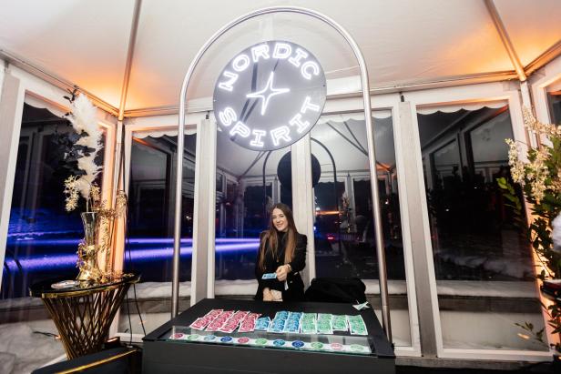 Eine Frau steht hinter einem Tresen mit bunten Dosen, über ihr leuchtet ein rundes Nordic Spirit Schild.