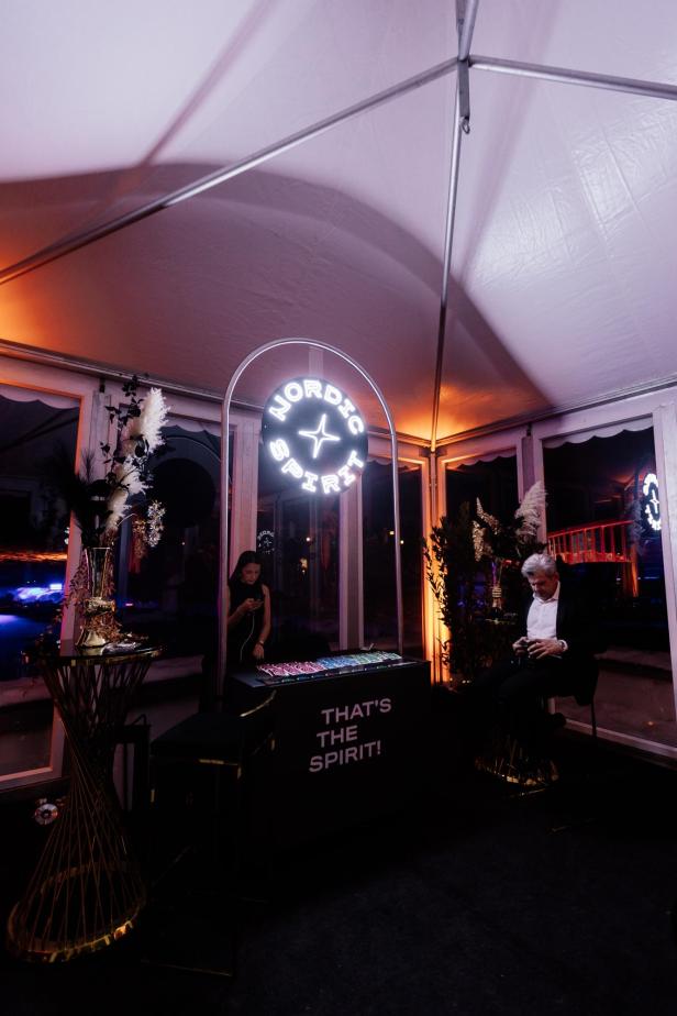Ein festlich dekorierter Raum mit einem beleuchteten „Nordic Spirit“-Schild, zwei Personen und einem Tisch mit der Aufschrift „That's the spirit!“.