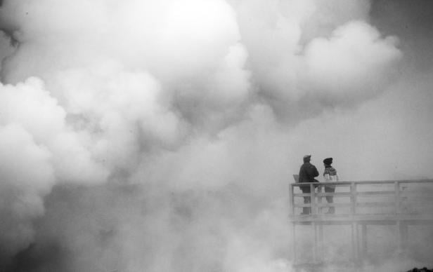 Zwei Menschen stehen auf einer hölzernen Plattform und blicken in dichten Nebel, der Unsicherheit und die lange Suche nach einer Diagnose bei seltenen Erkrankungen symbolisiert.