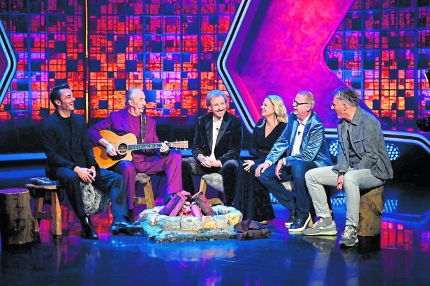 meheree moderatoren, einer spielt gitarre am plastiklagerfeuer