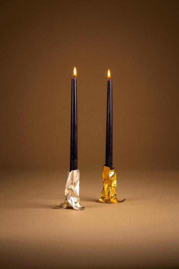 Goldener Kerzenständer mit schwarzen brennenden Kerzen