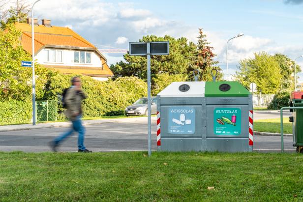 Ein Mann eilt zu einem Glascontainer.