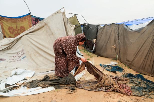 Displaced Palestinians shelter in a tent camp on a rainy day in Khan Younis