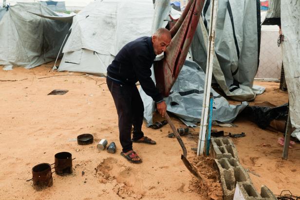 Displaced Palestinians shelter in a tent camp on a rainy day in Khan Younis