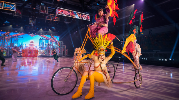 Holiday on Ice - Eiskunstläufer*innen fahren mit sehr großem Rad auf Eis