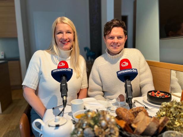 Zwei Personen sitzen beim Frühstück mit Hitradio Ö3 Mikrofonen am Tisch.
