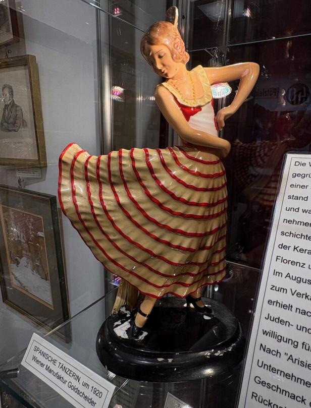 Keramikfigur einer spanischen Tänzerin mit gelbem Kleid und roten Streifen, eine Hand in die Hüfte gestützt.