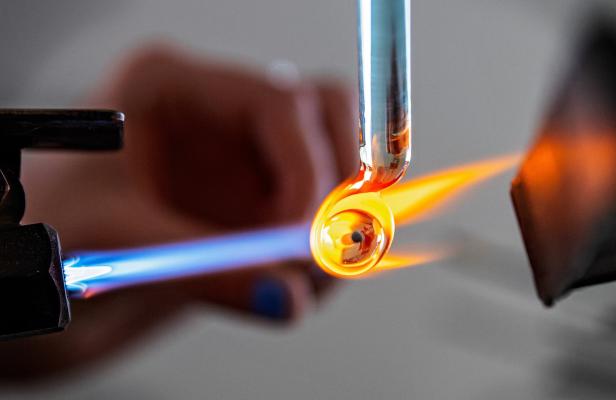 Die Glaskunstarbeit: Ein Glastäbchen wird mit einer Gasflamme geschmolzen.