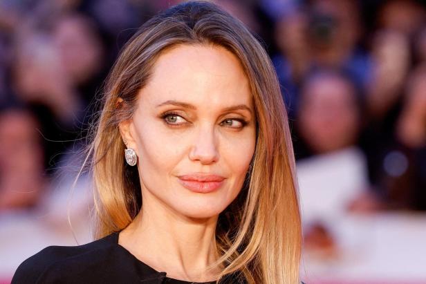 Angelina Jolie mit blondem Haar und Ohrringen blickt zur Seite.
