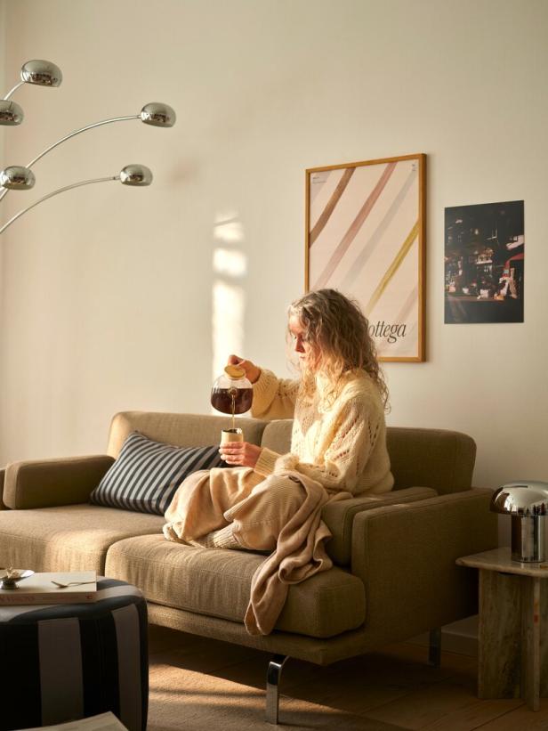 Frau sitzt auf Sofa und gießt Tee ein