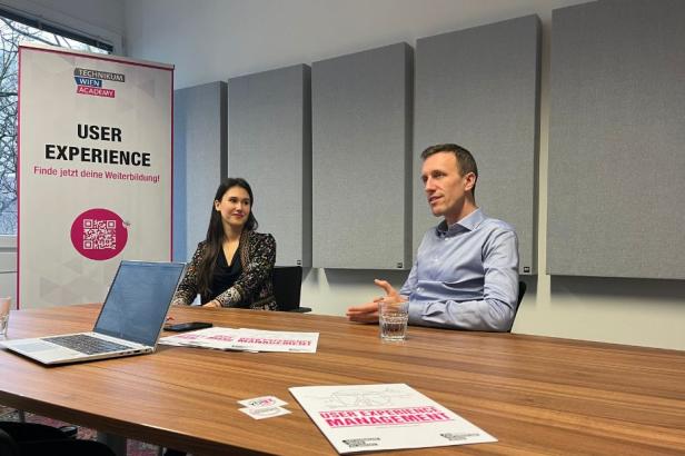 eine Frau und ein Mann sitzen an einem Tisch und werden interviewt.