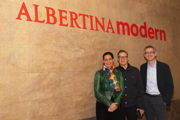 Bryan Adams steht mit Bettina Busse und Ralph Gleis vor dem Schriftzug „Albertina modern“ in Wien.