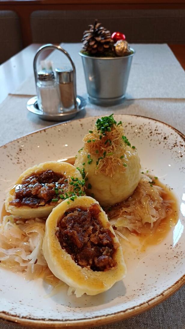 Zwei Grammelknödel, einer davon auseinandergeschnitten.  