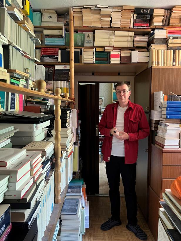 Franco Schedl steht vor seinen Büchern