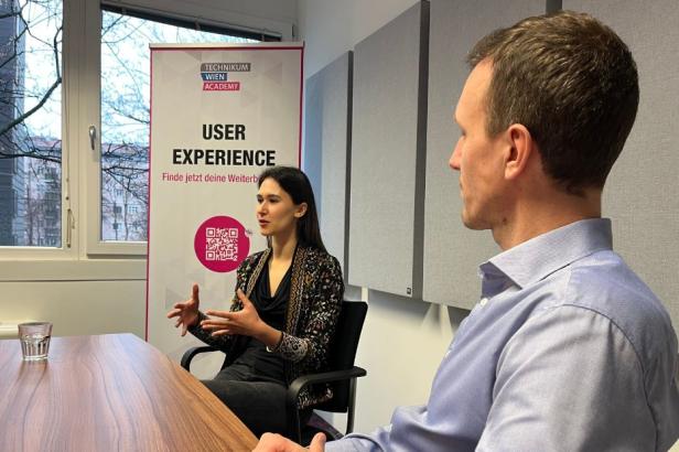 Zwei Personen sitzen in einem Konferenzraum an einem Tisch für ein Interview.