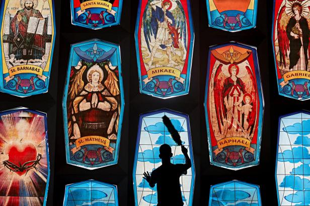 A worker cleans a mosaic glass window at Saint Barnabas Catholic Church to prepare for the Christmas Mass, in South Tangerang