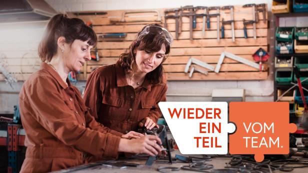 Zwei Frauen in einer Werkstatt, die gemeinsam an einem Tisch arbeiten.