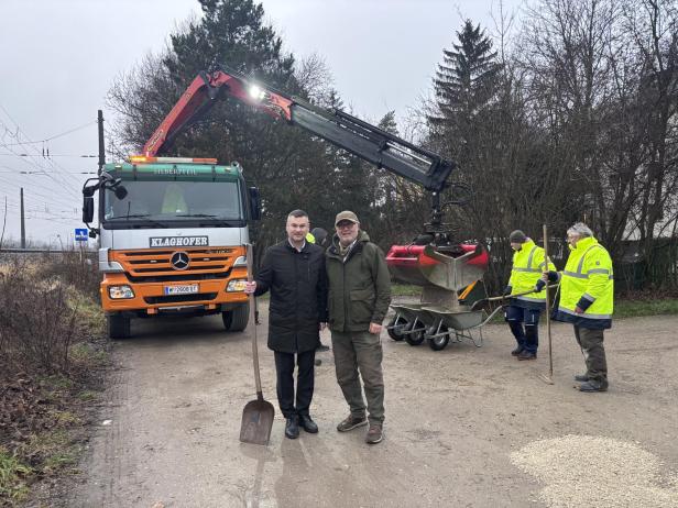 Zwei Männer mit Schaufel vor einem Lastwagen bei Bauarbeiten