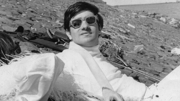 "Mr. Scorsese" mit Sonnenbrille und hellem Rollkragenpullover liegt entspannt im Freien.