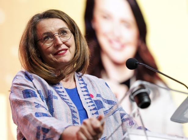 Die Politikerin Selma Arapovic spricht lächelnd an einem Rednerpult vor einem unscharfen Hintergrund.